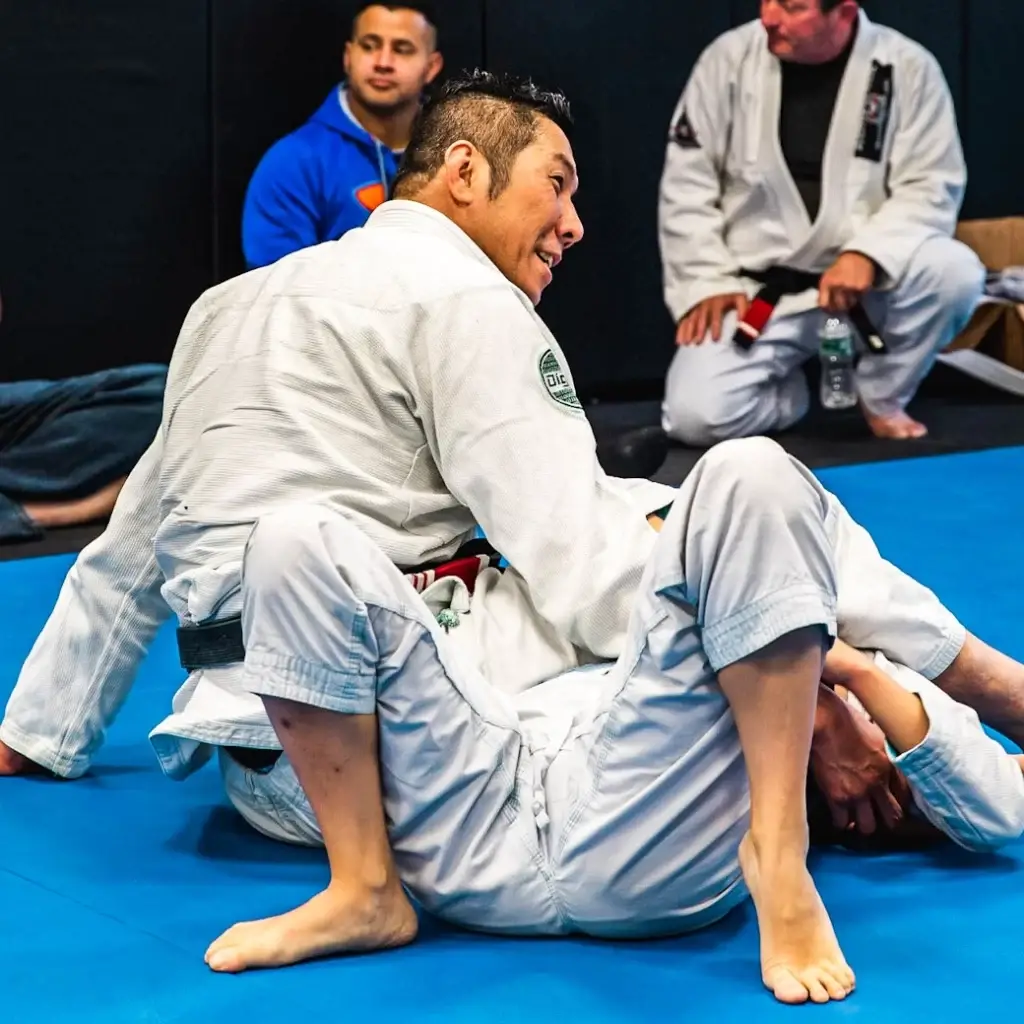 "Brazilian Jiu Jitsu instructor demonstrating a mount position during class while students observe at Caio Terra Academy.
