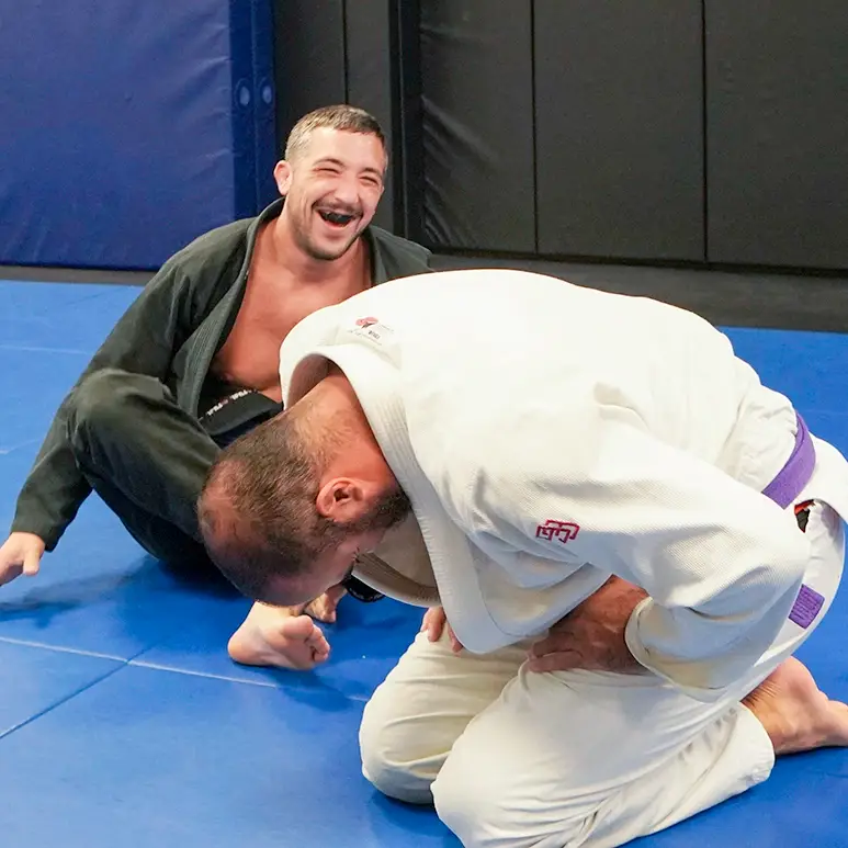 Two Brazilian Jiu Jitsu students laughing and enjoying training on the mat at Caio Terra Academy Long Island.